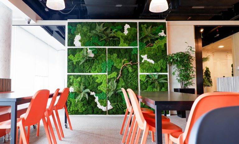 Three freestanding living green wall partitions create natural dividers in a bright modern office with collaborative workspaces and contemporary furniture.